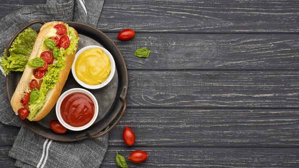 Flat lay hot dog with sauce bowls