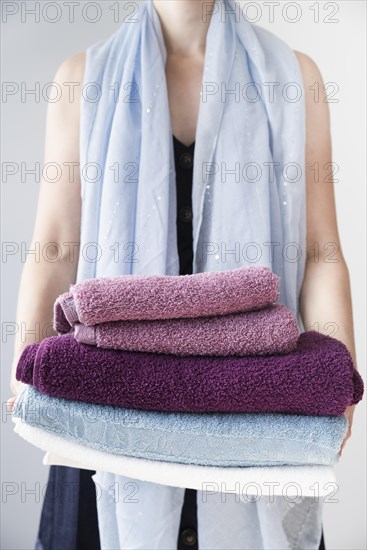 Front view person holding stacked towels