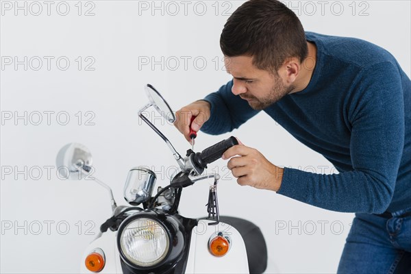 Front view young man fixing motorcycle