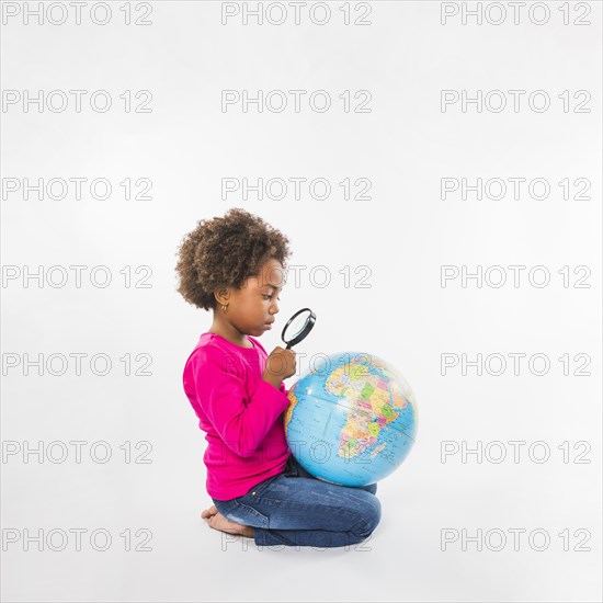 Girl exploring globe with loupe studio