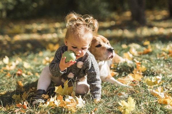 Girl playing with ball sitting grass near her dog park