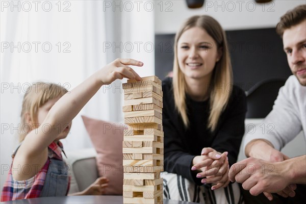 Girl putting block tower near parents