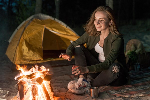 Girl warming up by campfire