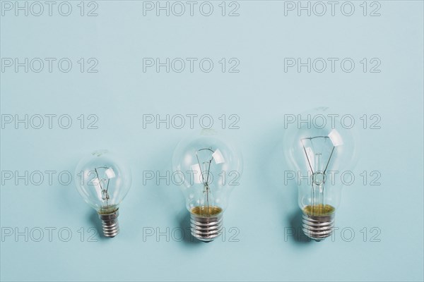 Growing up transparent light bulb blue background