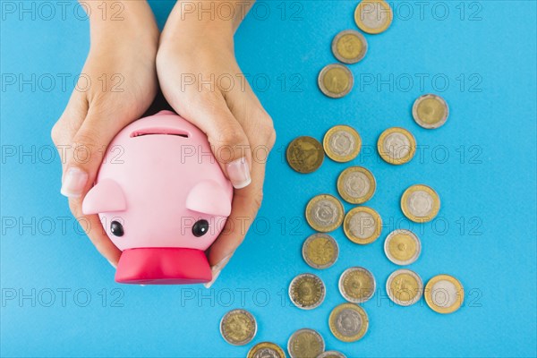 Hands holding piggy bank table with coins