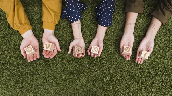 Hand s holding social media app icons wooden blocks green grass