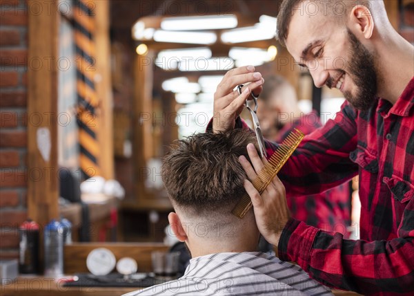 Handsome hairdresser making hipster haircut