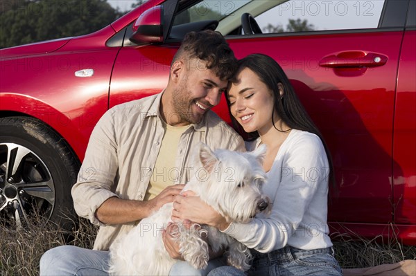 Happy couple holding dog medium shot