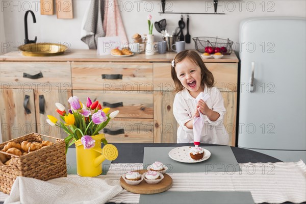 Happy little girl making cupcake