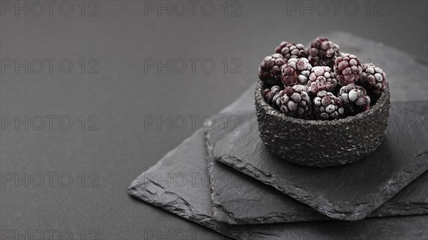 High angle frozen blackberries bowl with slate