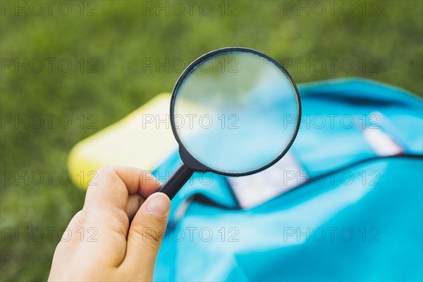Holding magnifier increases background backpack grass