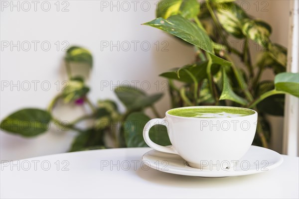 Hot matcha green tea cup saucer white table