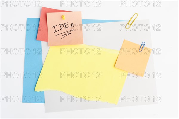 Idea text written sticky note with pushpin paperclip white board