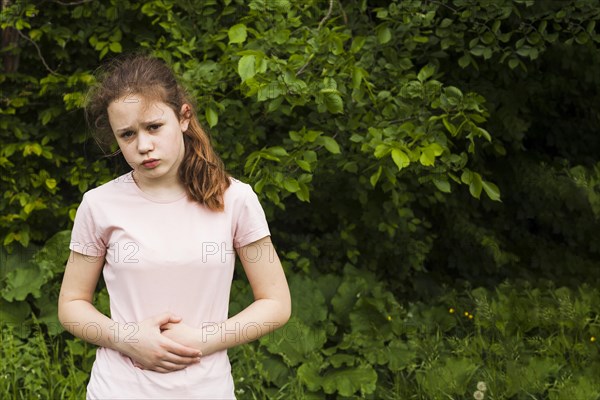 Innocent girl holding her stomach while having stomach pain park