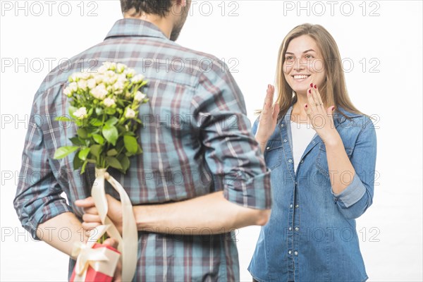 Man hiding flower gift his back front smiling girlfriend