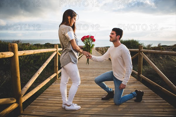 Man kneeling handing bouquet roses woman