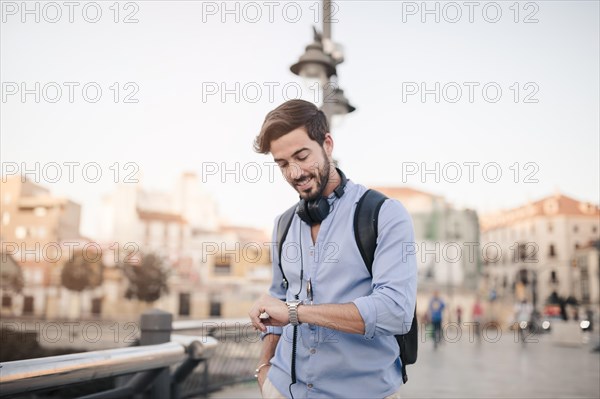 Man standing front city building looking time watch