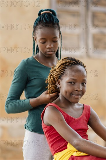 Medium shot girl braiding friend s hair