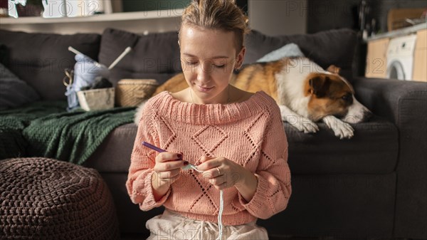 Medium shot woman crocheting with dog