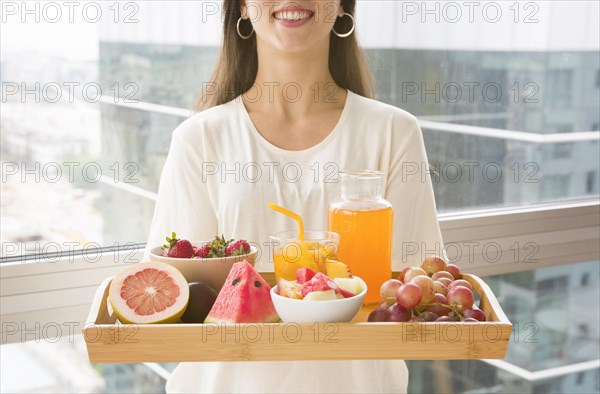Midsection woman holding wooden tray with many fruits juice