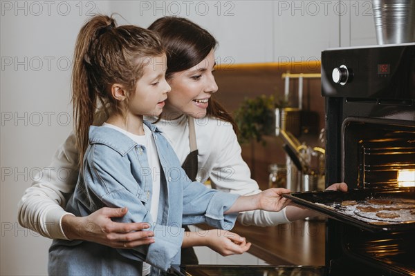 Mother daughter baking cookies home together