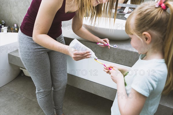 Mother daughter putting toothpaste brushes