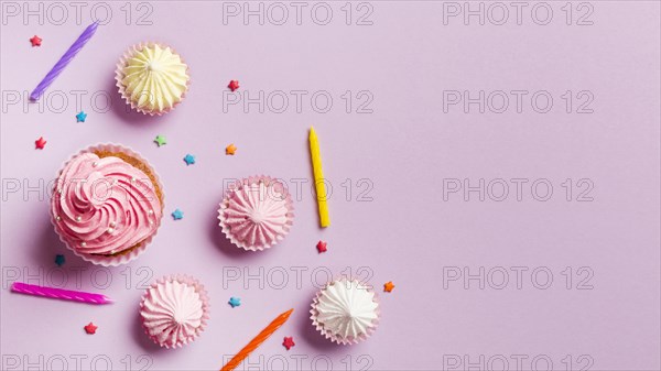 Muffins candles aalaw sprinkles against pink background