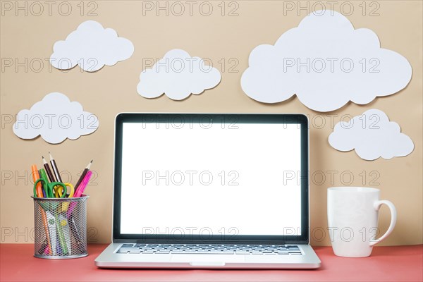 Mug stationery near laptop clouds