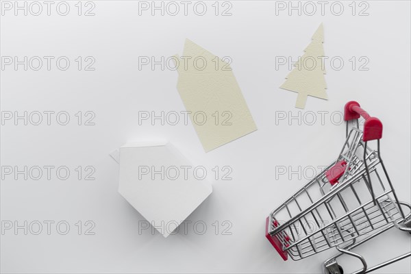 Paper cut out house christmas tree with miniature house model shopping cart isolated white background