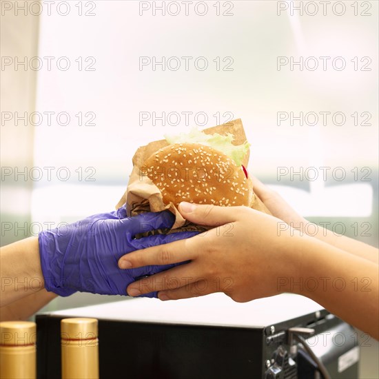 Person getting hamburger from fast food worker