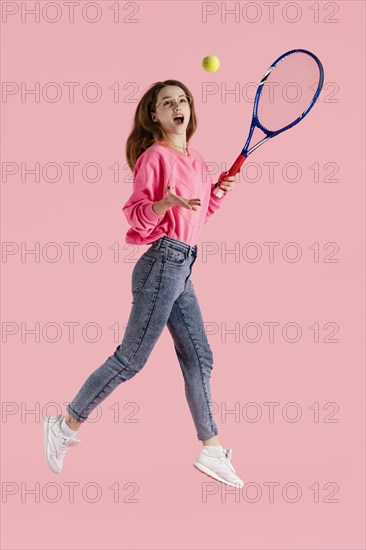 Portrait happy woman jumping with tennis racket