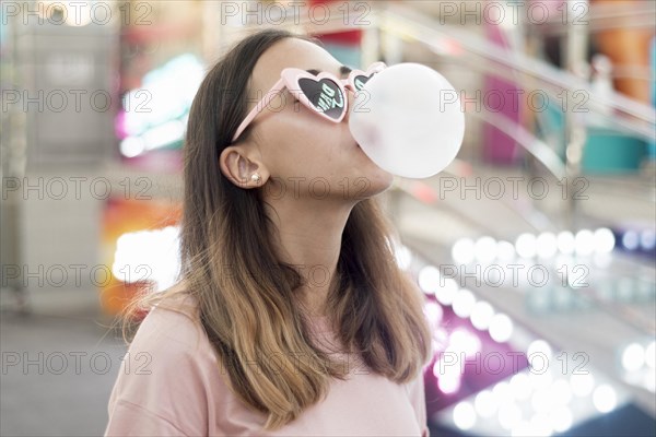 Portrait young girl blowing bubble gum