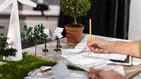 Side view man working eco friendly wind power project with paper plans