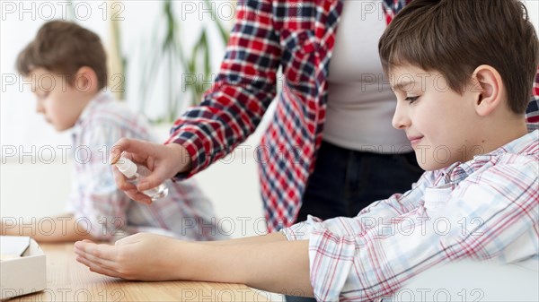 Side view mother spraying sanitizer child s hands