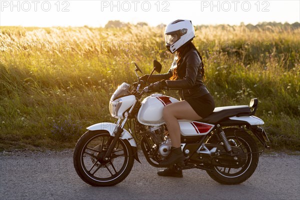 Side view woman riding motorcycle with helmet