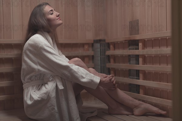 Side view young woman sitting wooden bench sauna