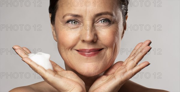 Smiley elder woman with foaming cleanser her hand