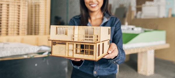 Smiling african american woman showing model house