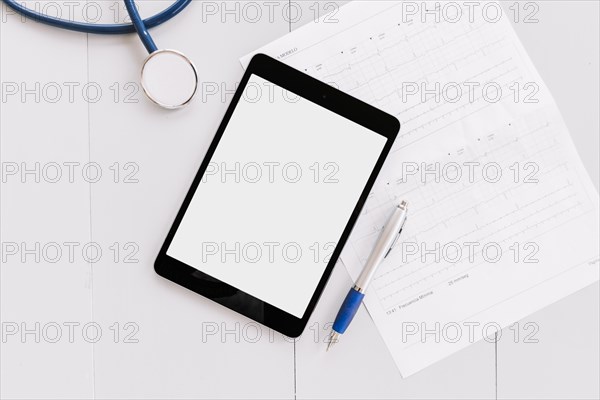 Stethoscope digital tablet pen cardiogram chart white wooden surface