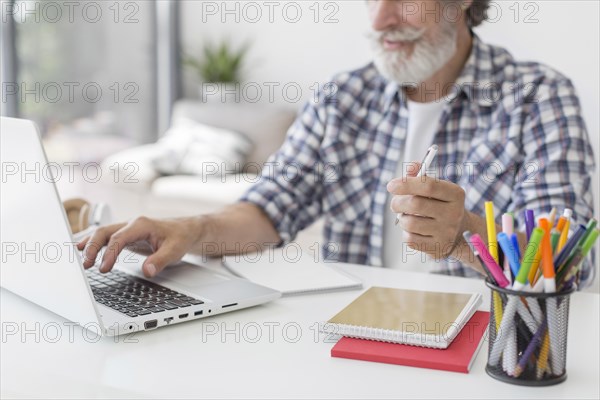 Teacher holding pen using laptop