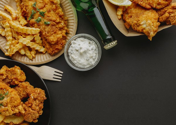 Top view fish chips plates with cutlery beer bottle