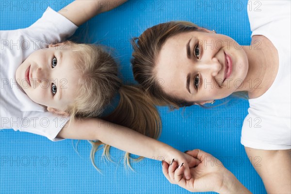 Top view happy mother posing with daughter yoga mat