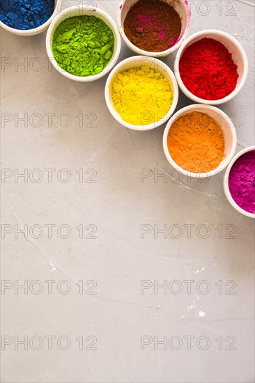 Top view multi colored holi powder white bowls concrete backdrop