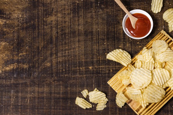 Top view potato chips with ketchup copy space