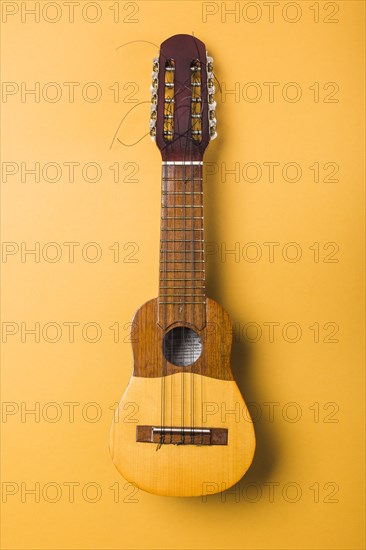 Ukulele with broken string yellow background