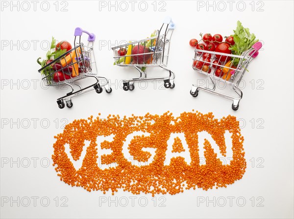 Vegan lettering with delicious vegetables small shopping carts