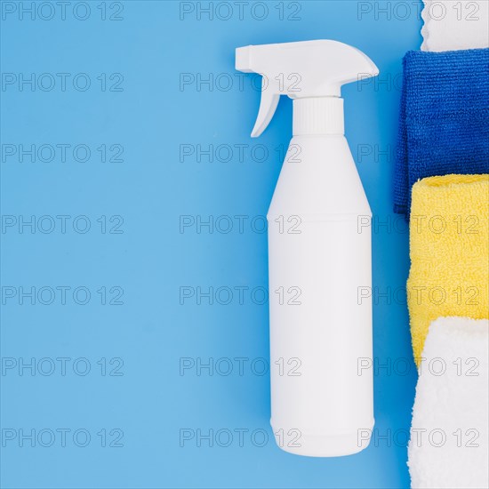 White spray bottle near colorful folded napkin blue background