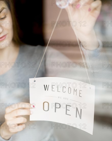 Woman putting open sign window coffee shop