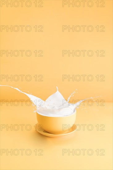 Yellow cup with spilling milk