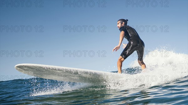 Young man surfs ocean waves